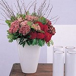 A white vase with pink/red flowers brings romance
